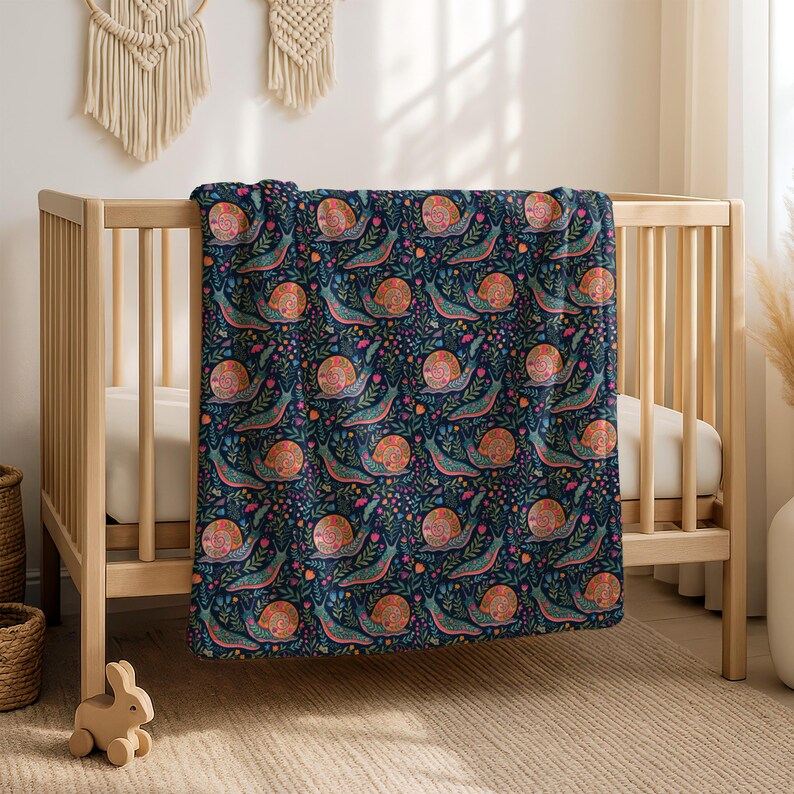 Floral snail pattern on a dark blue baby blanket draped over a crib.