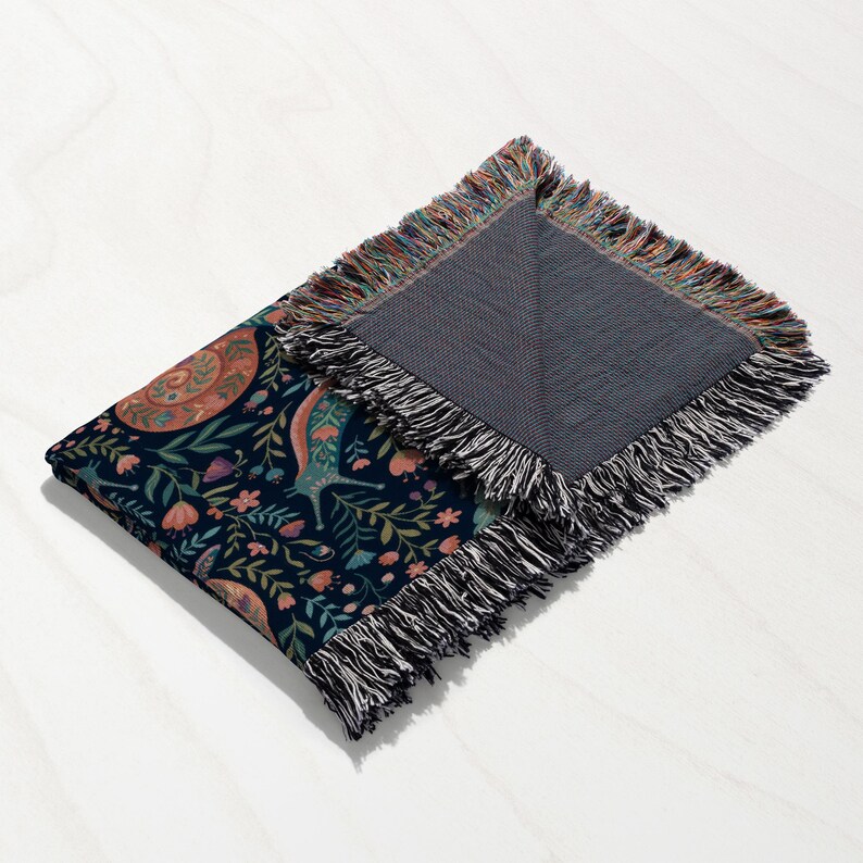 Navy blanket with intricate floral and animal pattern and fringed edges.