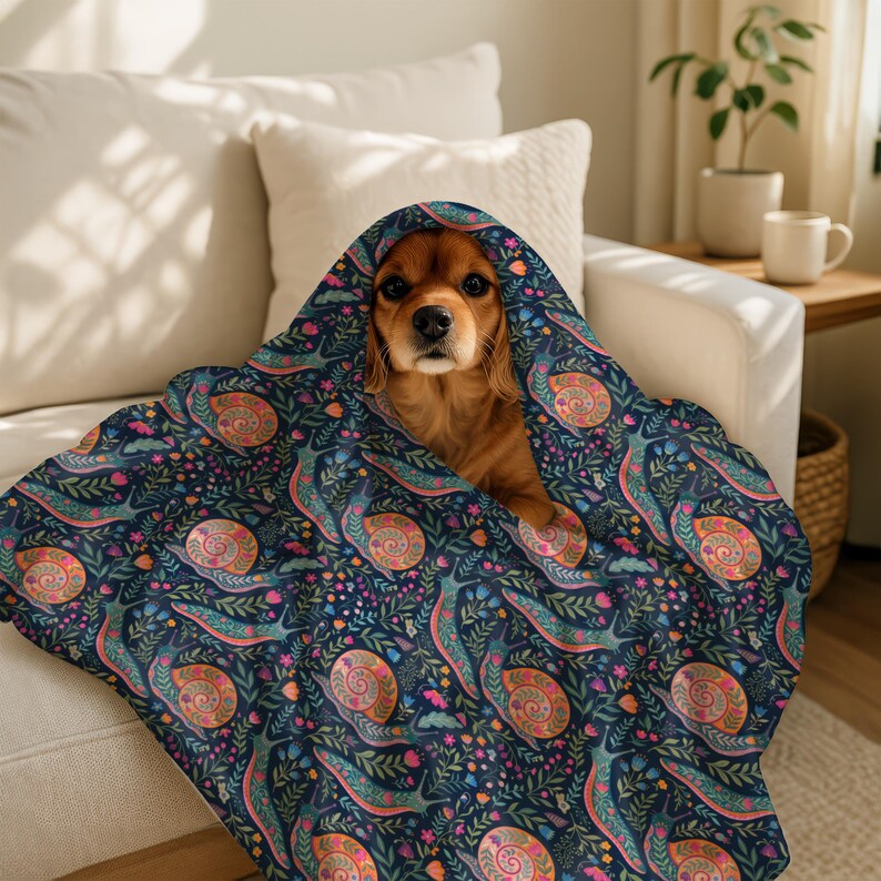 Cavalier King Charles Spaniel peeking out from under a colorful snail-patterned blanket.