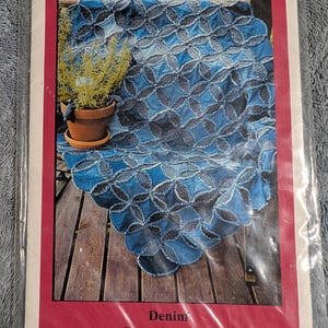 May include: A sewing pattern packet titled Bonnie B Buttons Denim Stars & Circles #9800. The cover features a blue denim quilt with a circular and star-like pattern, draped over a wooden surface next to a potted plant in a terracotta pot.