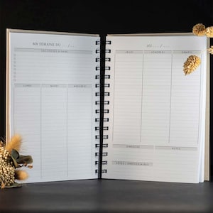 Peut inclure: Un agenda hebdomadaire blanc avec une reliure spirale noire. L'agenda comporte des sections pour chaque jour de la semaine, ainsi qu'une section pour les notes et les occasions spéciales.