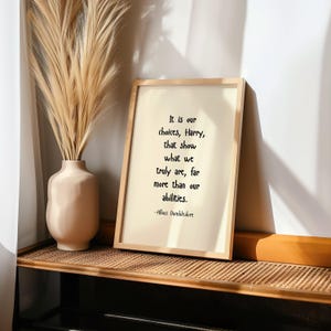 May include: A framed print with a quote from Albus Dumbledore, "It is our choices, Harry, that show what we truly are, far more than our abilities." The quote is printed in black ink on a white background.