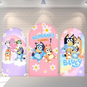 May include: Three arched fabric backdrops featuring cartoon dog characters and daisy patterns. The left panel is purple, the centre is pink with the text Kehlani's Turning 1, and the right panel is pastel with the text Bluey and dog illustrations.