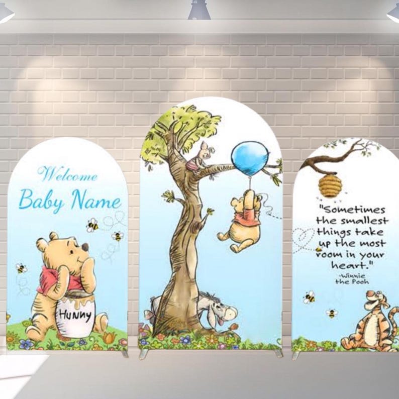 K&ouml;nnte beinhalten: Ein Set aus drei bogenf&ouml;rmigen Schildern zum Thema Winnie Puuh. Die Schilder zeigen Illustrationen von Puuh, Ferkel, Eeyore und Tigger, zusammen mit Zitaten und dem Text "Welcome Baby Name". Die Schilder sind mit Bienen und Blumen verziert.
