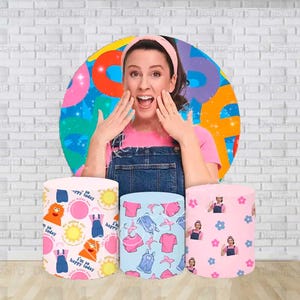 May include: Three cylindrical objects with colorful patterns. One is light pink with a repeating pattern of a cartoon character, sun, and text. Another is light blue with clothing graphics. The third is pink with a repeating pattern of a person and flowers.