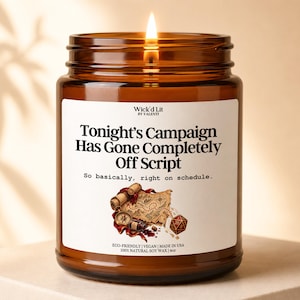 May include: A 4oz amber glass jar candle with a lit wick. The white label reads: Wick'd Lit BY VALENTI, Tonight's Campaign Has Gone Completely Off Script, So basically, right on schedule. Below is an illustration of a map, compass, and 20-sided die.