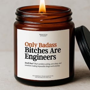 Könnte beinhalten: Ein brennendes bernsteinfarbenes Glas-Kerzenglas mit schwarzem Deckel. Die Kerze hat ein weißes Etikett mit dem Text "Only Badass Bitches Are Engineers". Die Kerze wird aus 100 % natürlichem Sojawachs hergestellt und ist umweltfreundlich und vegan.