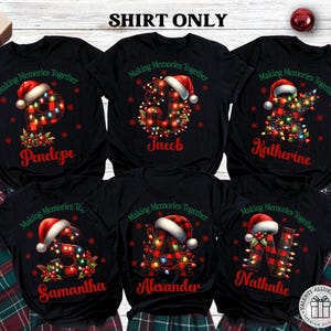 May include: Black t-shirts with personalized Christmas designs. Each shirt features a letter decorated with lights and a Santa hat, with a name below. The text "Making Memories Together" is above the letter. Plaid pajama pants are visible.