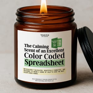 May include: A lit soy wax candle in a brown glass jar with a black lid. The label reads "The Calming Scent of an Excellent Color Coded Spreadsheet." The candle is eco-friendly, vegan, and made in the USA.