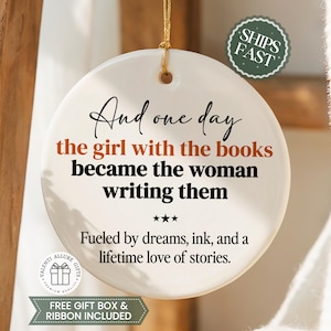 May include: A white ceramic ornament with the quote "And one day the girl with the books became the woman writing them." The ornament has a gold string for hanging and includes the text "Fueled by dreams, ink, and a lifetime love of stories."