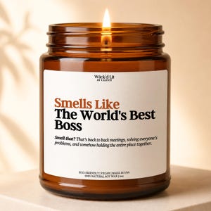 May include: A lit candle in a brown glass jar with a white label. The label reads Wick'd Lit by Valenti, Smells Like The World's Best Boss, and includes descriptive text about meetings and 4oz, 100% natural soy wax, eco-friendly, vegan, made in USA.