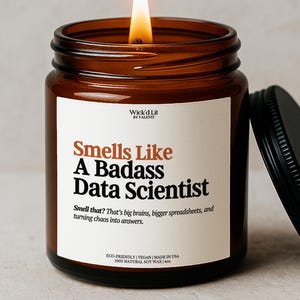 May include: A lit amber glass candle jar with a black lid. The label reads "Smells Like A Badass Data Scientist." The text below says "Smell that? That's big brains, bigger spreadsheets, and turning chaos into answers." The candle is eco-friendly and made with natural soy wax.