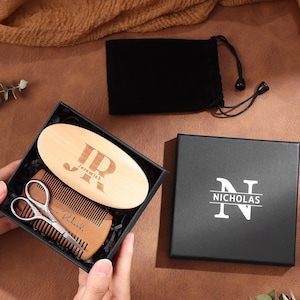 May include: A personalized beard grooming kit in a black gift box. The kit includes a wooden brush with initials and name, a wooden comb, and small scissors. A black drawstring bag and a box with the name "Nicholas" are also included.