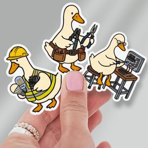 May include: Three die-cut stickers featuring cartoon ducks performing electrical work. One duck wears a yellow hard hat and high-visibility vest, another wears a brown tool belt holding pliers, and the third sits on a stool using a screwdriver on a panel.