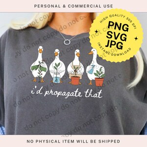 May include: Dark gray sweatshirt featuring a whimsical illustration of four white ducks, each tending to plants. The text "i'd propagate that" is below the ducks. A yellow sticker indicates instant download of PNG, SVG, and JPG files.