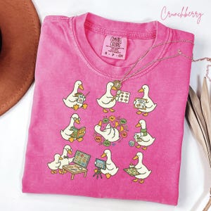 May include: A white ceramic mug with a black handle and the text "But First, Coffee" in a bold, black font. The mug is set against a blurred background, suggesting a cozy setting.