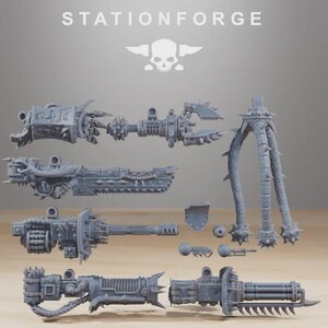 May include: A selection of grey miniature weapon components, including cannons, claws, and spiked legs. The word "STATIONFORGE" is printed at the top, with a skull and wings logo. The pieces are arranged on a light brown surface.
