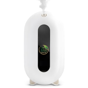 Pode incluir: Um difusor de óleos essenciais branco com uma janela vertical preta e um logotipo que diz "Dr. Biss Natural Care". O difusor tem uma forma arredondada, pés pequenos e emite vapor pela parte superior.