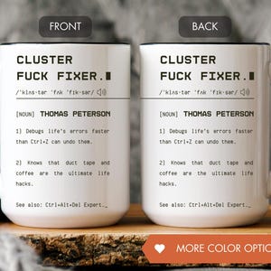 Op de afbeelding: Witte keramische mok met zwarte handgreep en rand. De mok heeft de tekst "CLUSTER FUCK FIXER" met een definitie en de naam "THOMAS PETERSON". De mok bevat ook twee humoristische uitspraken.