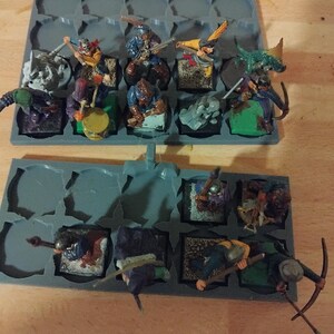 Peut inclure: Un plateau de rangement en plastique gris avec des compartiments pour ranger des figurines miniatures. Le plateau est rempli de figurines miniatures peintes de guerriers, d'archers et d'autres personnages fantastiques. Les figurines sont peintes dans diff&eacute;rentes couleurs, notamment le vert, le bleu, le rouge et le jaune.