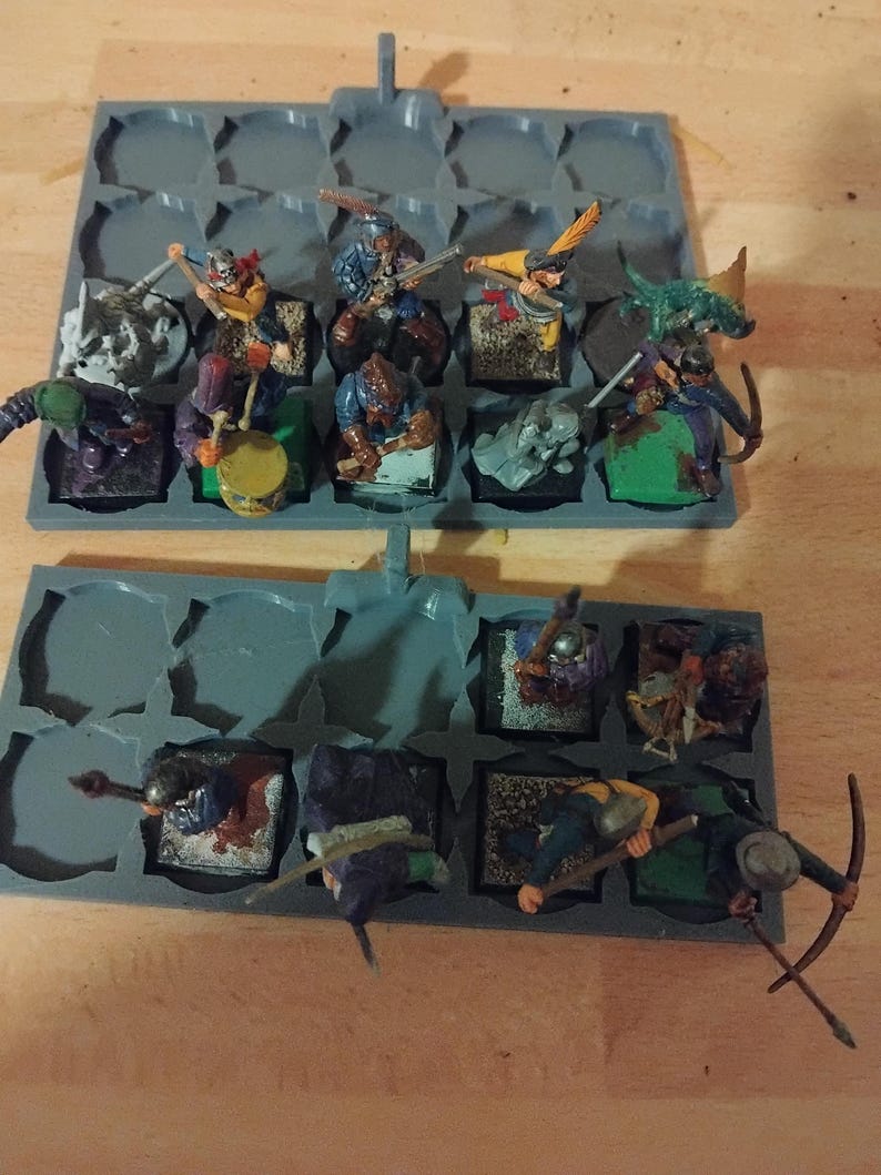 Peut inclure: Un plateau de rangement en plastique gris avec des compartiments pour ranger des figurines miniatures. Le plateau est rempli de figurines miniatures peintes de guerriers, d'archers et d'autres personnages fantastiques. Les figurines sont peintes dans diff&eacute;rentes couleurs, notamment le vert, le bleu, le rouge et le jaune.