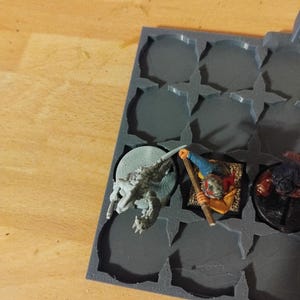 Peut inclure: Un plateau de rangement en plastique gris avec des compartiments pour figurines miniatures. Une figurine miniature grise et blanche d'une cr&eacute;ature avec une longue queue se trouve dans un compartiment. Une figurine miniature d'une personne avec une tenue rouge et jaune se trouve dans un autre compartiment. Une figurine miniature d'une cr&eacute;ature &agrave; fourrure brune se trouve dans un troisi&egrave;me compartiment.