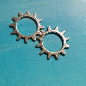 May include: Two silver metal gears with a blue background.