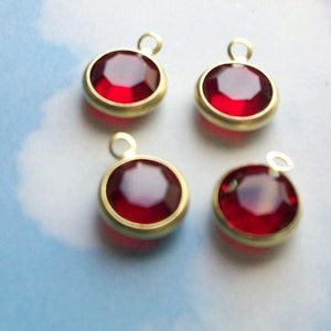 May include: Four gold-toned charms with red glass stones. Each charm has a loop for attaching to a necklace or bracelet.