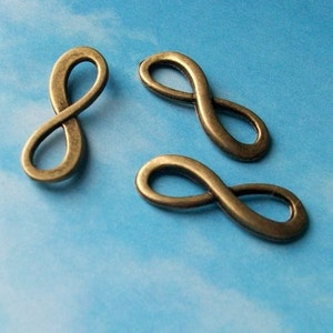 May include: Three antique gold-toned infinity symbol charms. The charms are made of metal and have a smooth, polished finish.