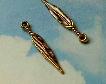 May include: Two gold-toned metal feather charms with a loop at the top for attaching to jewelry or other crafts.
