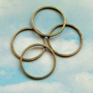 May include: Four antique gold-toned metal rings, stacked on top of each other. The rings are round and have a smooth, polished finish.
