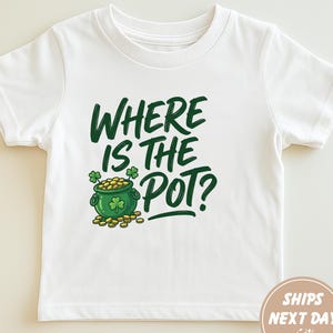 以下が含まれることがあります： 「WHERE IS THE POT？」の文字と、クローバーと金の入った漫画のポットが描かれた緑色のグラフィックが特徴の白いTシャツ。聖パトリックの日の祝賀に最適です。