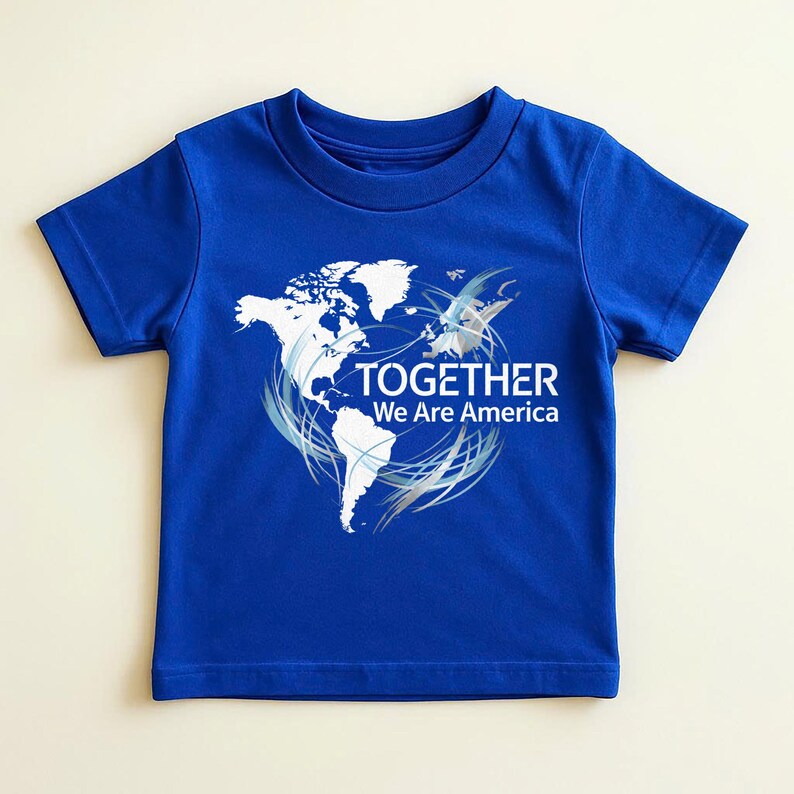 Puede incluir: Una camiseta azul real con un contorno blanco de las Am&eacute;ricas y la frase "TOGETHER We Are America". El dise&ntilde;o incluye remolinos plateados y un gr&aacute;fico estilizado de un p&aacute;jaro. La camiseta est&aacute; hecha de un material suave.