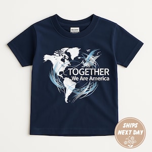 Puede incluir: Camiseta azul marino con un gr&aacute;fico de mapa del mundo blanco y el texto "TOGETHER We Are America". El dise&ntilde;o incluye remolinos azules y plateados. La camiseta es de material suave.
