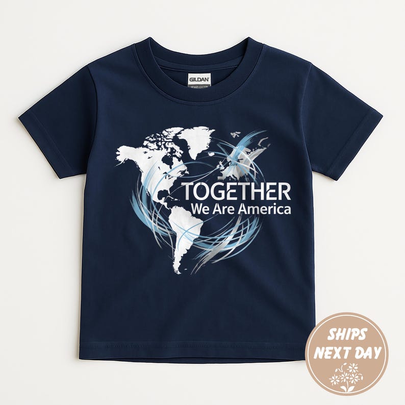Puede incluir: Camiseta azul marino con un gr&aacute;fico de mapa del mundo blanco y el texto "TOGETHER We Are America". El dise&ntilde;o incluye remolinos azules y plateados. La camiseta es de material suave.
