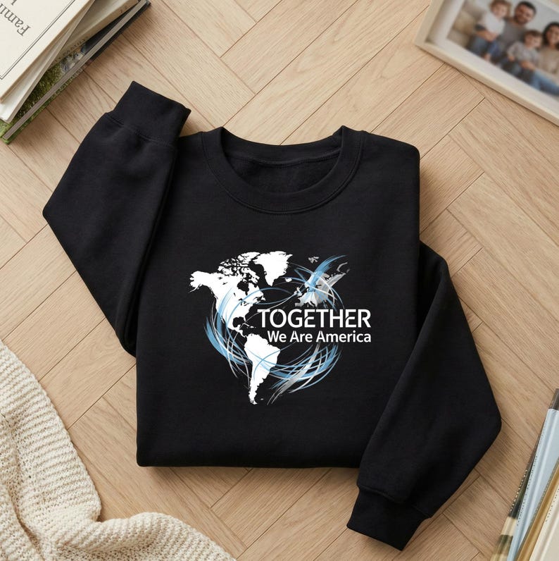 Puede incluir: Sudadera negra con un gr&aacute;fico blanco de un mapa del mundo y detalles en azul. El texto "TOGETHER We Are America" est&aacute; debajo del mapa. La sudadera est&aacute; hecha de un material suave.
