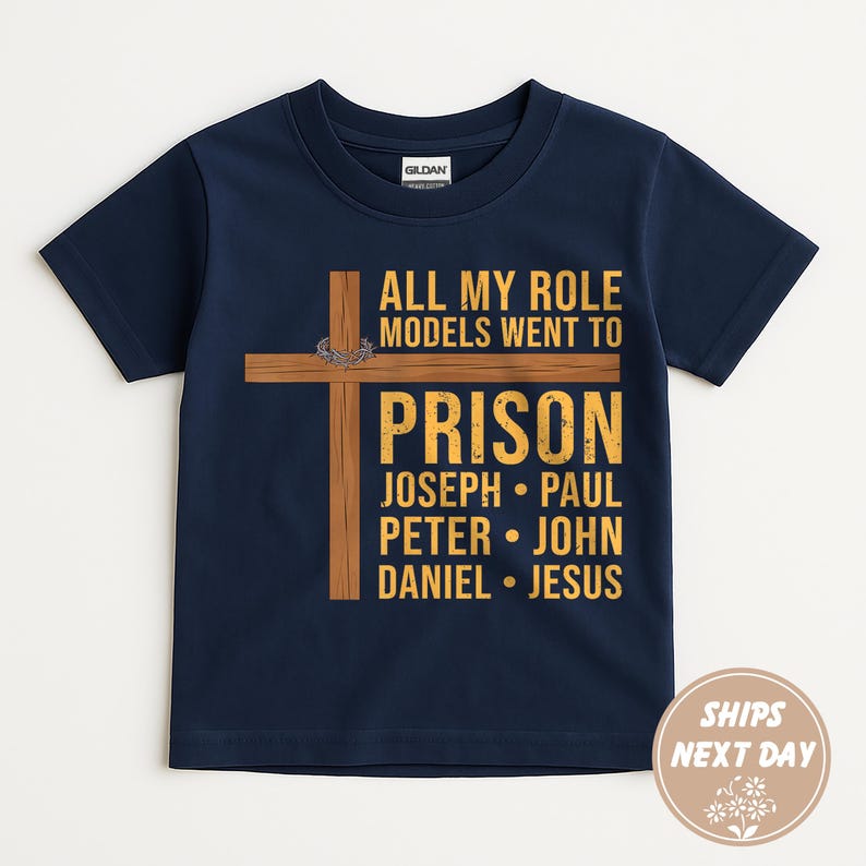 May include: Navy blue t-shirt with the text "ALL MY ROLE MODELS WENT TO PRISON" and a wooden cross graphic. The names Joseph, Paul, Peter, John, Daniel, and Jesus are listed below the word "PRISON".