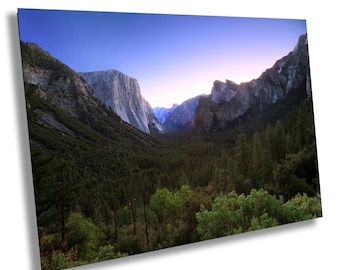 Könnte beinhalten: Ein Panoramablick auf ein Tal im Yosemite-Nationalpark, Kalifornien. Das Tal ist umgeben von hoch aufragenden Granitfelsen, mit einem üppigen Wald im Vordergrund. Der Himmel ist leuchtend blau, mit einem Hauch von Rosa in der Ferne.