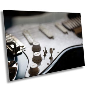 Puede incluir: Primer plano de una guitarra eléctrica azul con botones blancos y un botón "TONE" con los números del 1 al 6. La guitarra tiene una golpeador blanco y herrajes cromados.