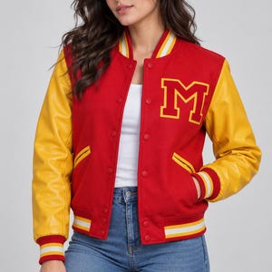 May include: A red varsity jacket with yellow sleeves, featuring a large yellow letter M patch on the left chest. The jacket has a snap-button front closure, ribbed collar, cuffs, and hem with white and yellow stripes, and two side pockets.
