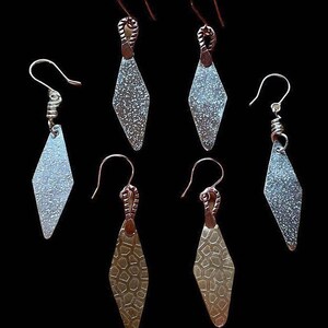 May include: Set of six silver and gold diamond-shaped earrings with textured surfaces. The earrings have a simple design and are perfect for everyday wear.