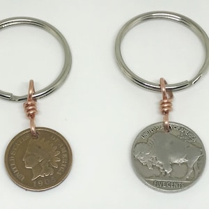 May include: Two keychains with copper wire accents. One keychain features a 1909 Indian Head penny and the other features a 1909 Buffalo nickel.