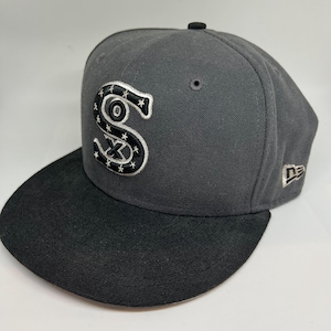 May include: A gray and black baseball cap with a black and white embroidered 'S' with stars on the front. The cap has a black brim and a black New Era logo on the side.