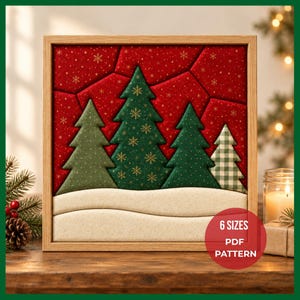 May include: A square framed fabric wall art piece featuring a red background with gold snowflakes, four stylized Christmas trees in varying shades of green and a white checkered pattern, and a cream-colored snowy base. Text reads 6 SIZES PDF PATTERN.