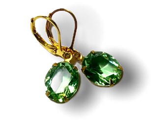 May include: A pair of gold earrings with green oval-shaped gemstones.