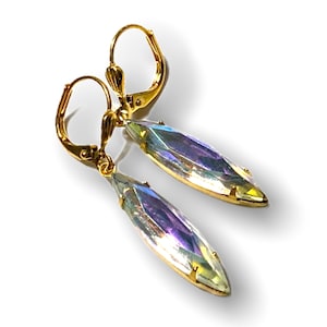 Op de afbeelding: Een paar gouden oorhangers met regenboogkleurige, druppelvormige kristallen.