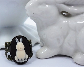 May include: A ring with a black cameo featuring a white rabbit. The cameo is set in a bronze filigree frame.