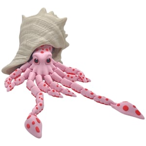 May include: A pink hermit crab toy with red spots, holding onto a beige shell. The toy has articulated legs and is made of a soft, pliable material.