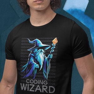 Puede incluir: Una camiseta negra con un mago azul sosteniendo un bastón y un diamante. El mago está rodeado de código binario. El texto "Coding Wizard" está impreso en la camiseta.