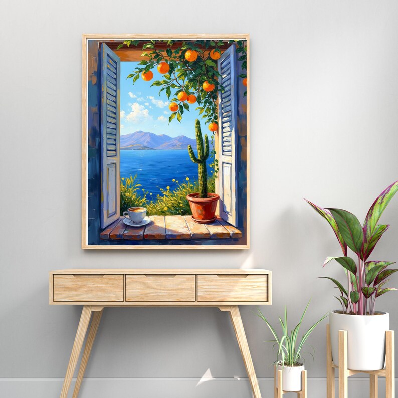 May include: A framed painting depicts a scenic view through an open window. The window reveals a blue sea, mountains, and a bright sky. A cactus in a terracotta pot sits on the windowsill, with a cup of coffee. Orange tree branches with ripe oranges frame the window.